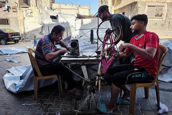 الخياط الفلسطيني شعبان الطباش يصلح أغطية بلاستيكية وقماشًا مشمعًا لتقوية خيام النازحين وحمايتها من برد الشتاء وأمطاره، في خان يونس جنوب قطاع غزة، 4 أكتوبر/تشرين الأول 2026. (تصوير: طارق محمد)