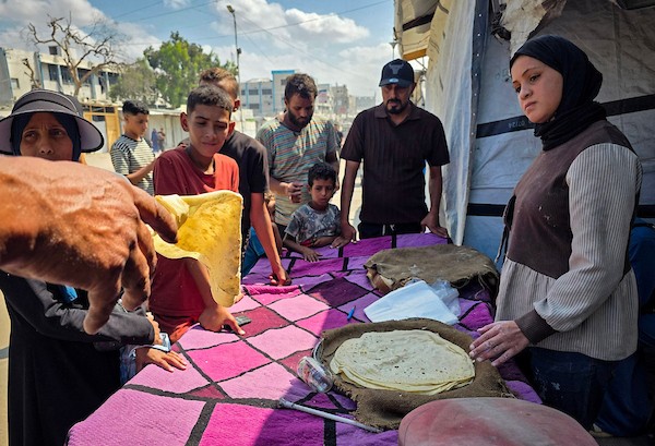 الفلسطيني مازن الدوش يُعدّ الخبز على صاج بدائي بين أنقاض المباني المدمرة في خان يونس، جنوب قطاع غزة، 9 تشرين الأول/أكتوبر 2026. (تصوير: طارق محمد)