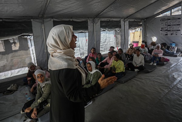 طلاب يتلقون دروسهم جلوسًا على الأرض داخل خيام تفتقر إلى المقاعد والتجهيزات المدرسية في مركز سرايا التعليمي بقطاع غزة، 11 أكتوبر/تشرين الأول 2026. (تصوير: محمد صالحة)