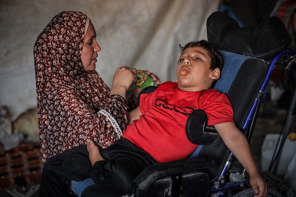 الطفلان الفلسطينيان إياد وميرا غبن، المصابان بالشلل الدماغي منذ الولادة، إلى جانب والديهما داخل خيمة نزوح غرب مدينة غزة، وسط نقص الرعاية الطبية والعلاج المتخصص، 29 أكتوبر 2026. (تصوير: محمد صالحة)