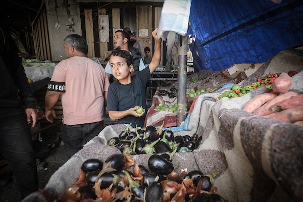 باعة فلسطينيون ومواطنون يقفون أمام أكشاك شبه خالية من الخضراوات والفواكه في أحد أسواق مخيم النصيرات وسط قطاع غزة، الخميس 22 أكتوبر 2026. تصوير: معز صالحي