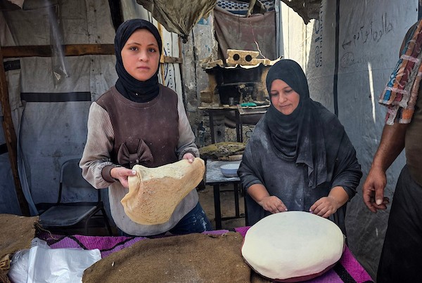 الفلسطيني مازن الدوش يُعدّ الخبز على صاج بدائي بين أنقاض المباني المدمرة في خان يونس، جنوب قطاع غزة، 9 تشرين الأول/أكتوبر 2026. (تصوير: طارق محمد)