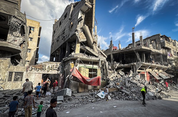 فلسطينيون يتفقدون ما تبقى من ممتلكاتهم وسط أنقاض مبنى سكني استهدفته غارة جوية إسرائيلية في مخيم المغازي للاجئين وسط قطاع غزة، يوم 16 أكتوبر/تشرين الأول 2026. (تصوير: أحمد إبراهيم)