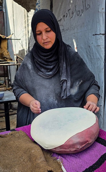الفلسطيني مازن الدوش يُعدّ الخبز على صاج بدائي بين أنقاض المباني المدمرة في خان يونس، جنوب قطاع غزة، 9 تشرين الأول/أكتوبر 2026. (تصوير: طارق محمد)