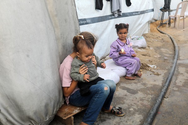 تحت أمطار غزة، يسير فلسطينيون نازحون وسط ظروف معيشية قاسية، فيما يحاول آخرون تغطية خيامهم لمنع تسرب مياه الأمطار إليها، في 18 أكتوبر/تشرين الأول 2026.تصوير: محمد صالحة